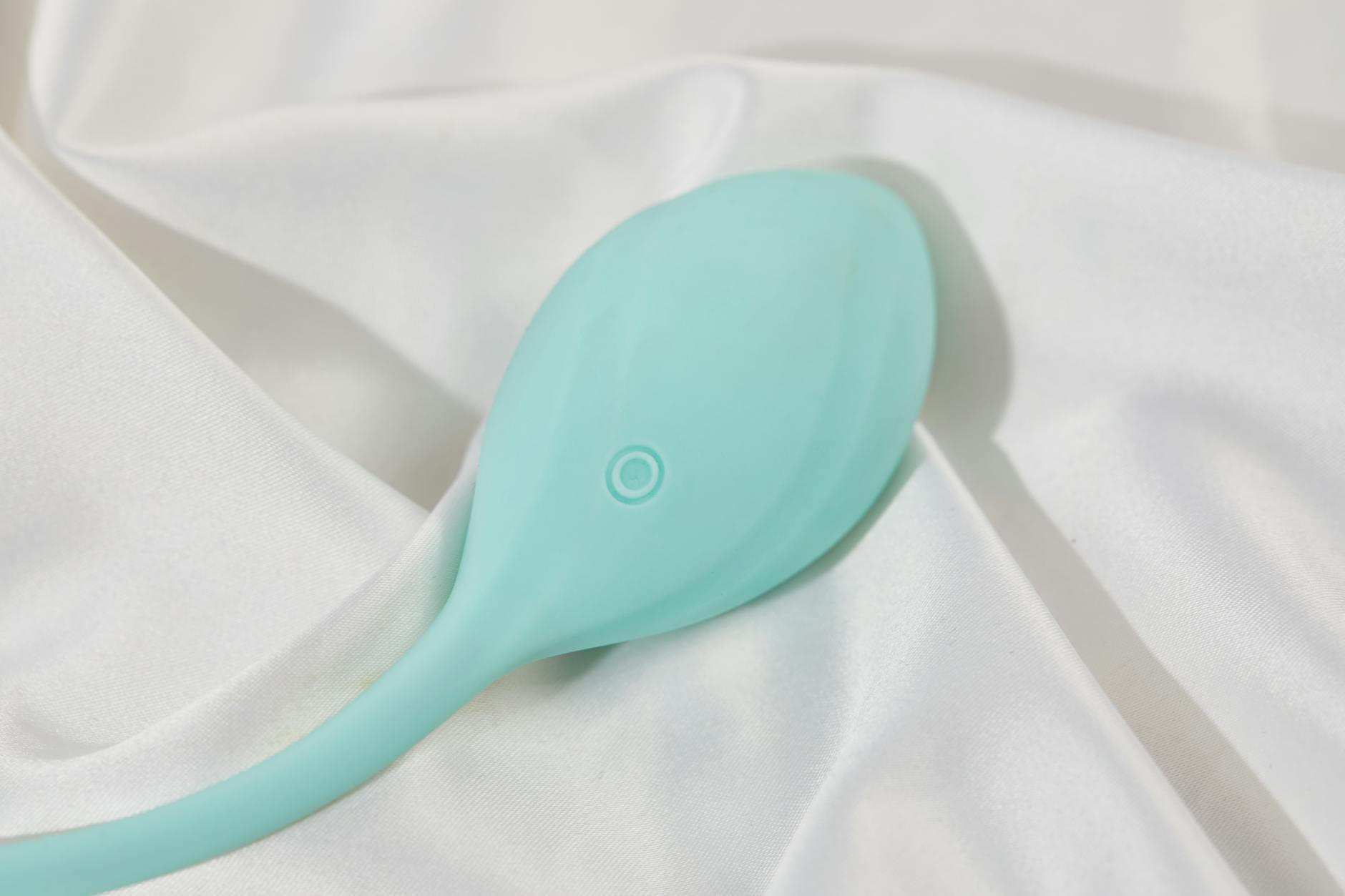 A sleek lemon vibrator on white silk, next to a pink wand vibrator for comparison