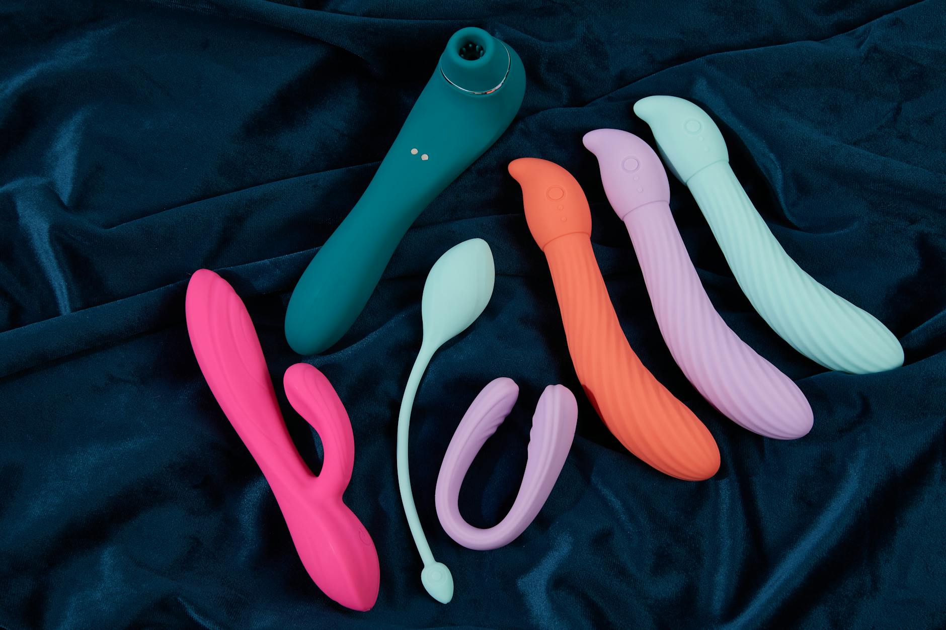 Woman holding a blue silicone vibrator thoughtfully, considering pleasure and self-connection.