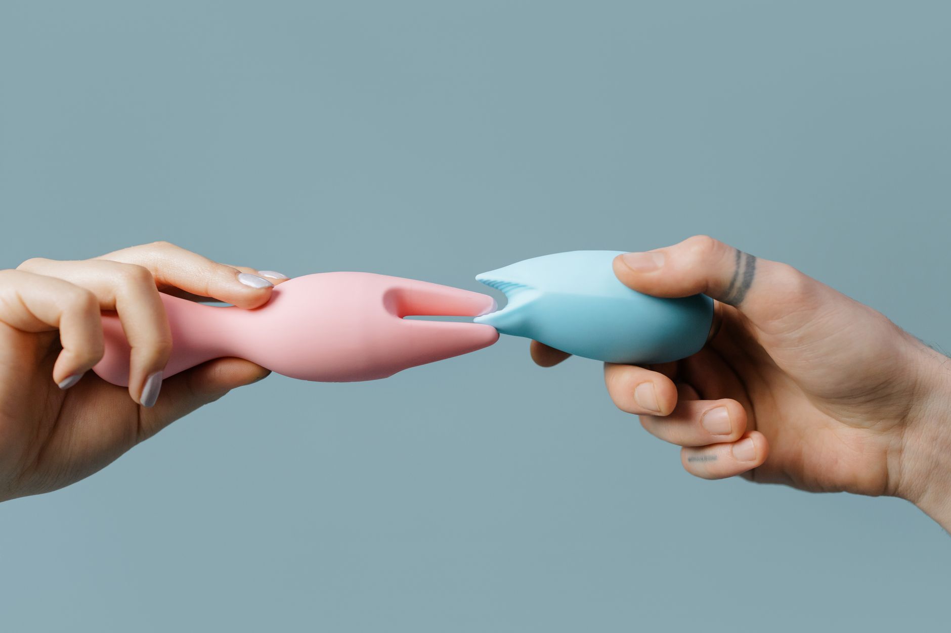 Hands holding colorful silicone vibrators, symbolizing pleasure and self-care after burnout