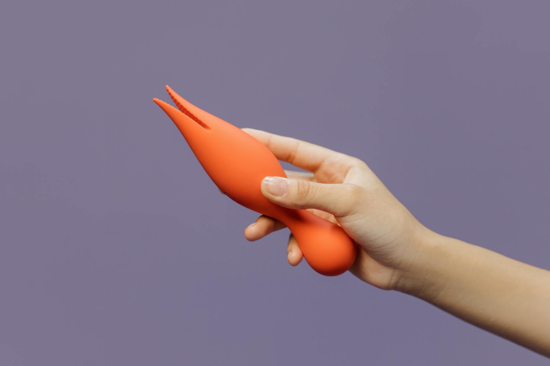 A hand holding a lemon vibrator against a minimalist purple background, symbolizing modern intimacy and communication.