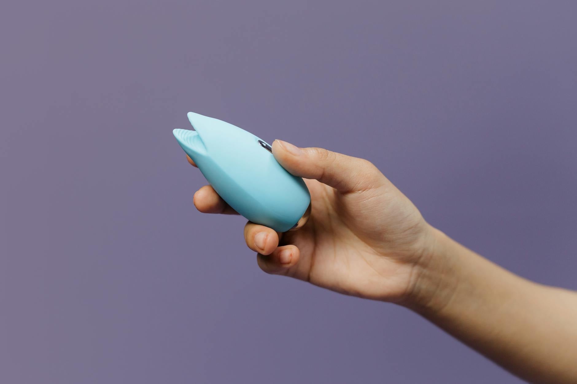 A yellow silicone vibrator surrounded by fresh fruit on a bright yellow background