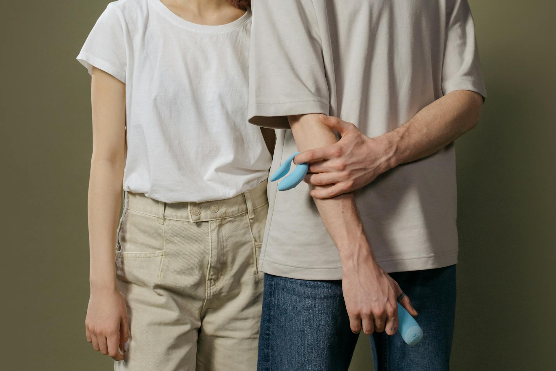Close-up of a hand holding an orange clitoral vibrator against a minimalistic purple backdrop