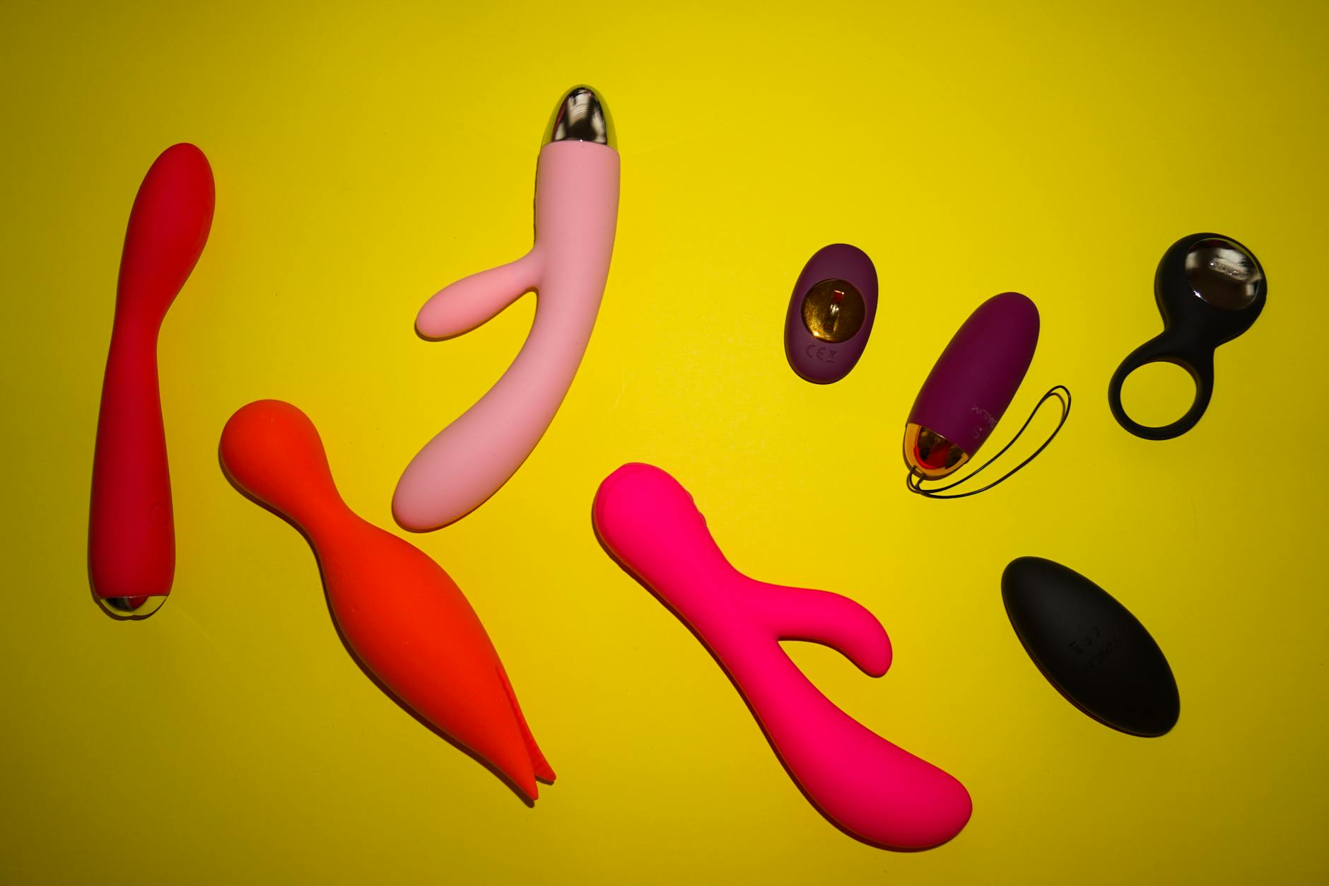 Woman holding blue and pink silicone clitoral vibrators in a contemplative moment