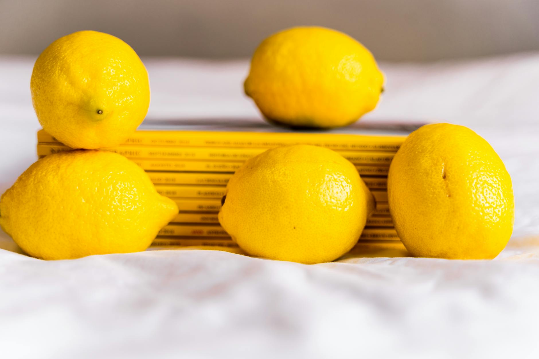 Fresh yellow lemons arranged with books on white surface